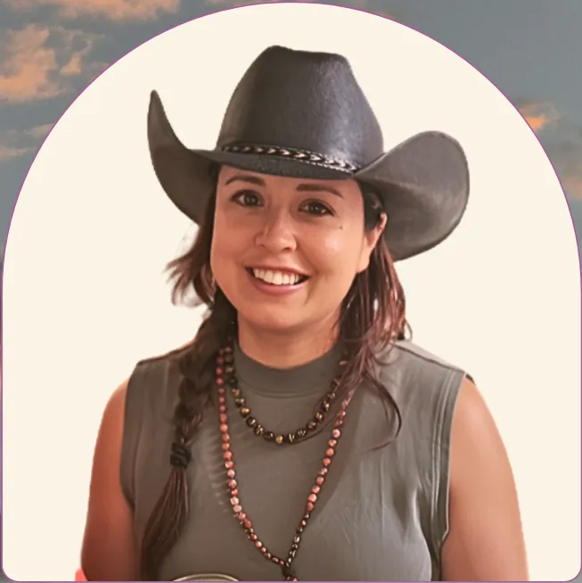 Mika in a cowboy hat, smiling, framed in an arch.